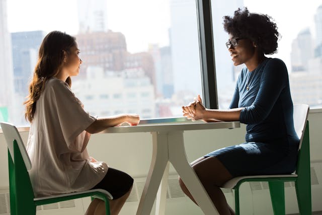 two people sitting down at a table having a conversation